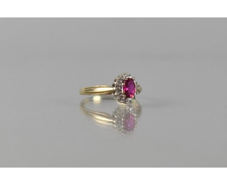 A Ruby, Diamond and 9ct Gold Cluster Ring, Central Oval Cut Ruby Measuring 6mm by 4mm, Raised in an Eight Claw Setting and Su