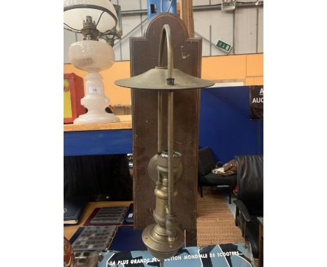 A VINTAGE BRASS LAMP ON A MAHOGANY BOARD 