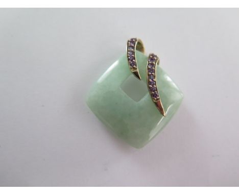 A cushion form pendant comprising of a section of jadeite jade, moss in snow-opaque, with a double yellow colour metal curl w