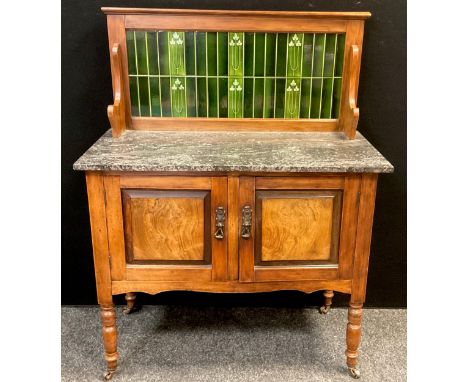 An early 20th century walnut Art Nouveau tile-back washstand, fossil stone top, over pair of cupboard doors, turned legs, bra