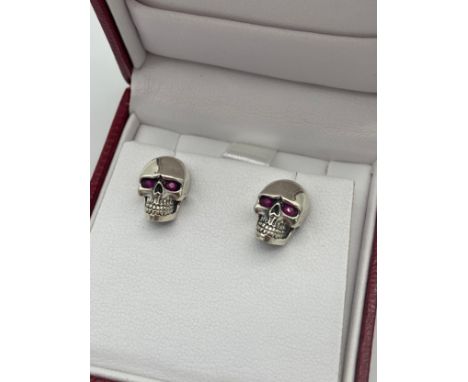 A Pair of Silver 925 skull earrings with ruby cultured eyes. 