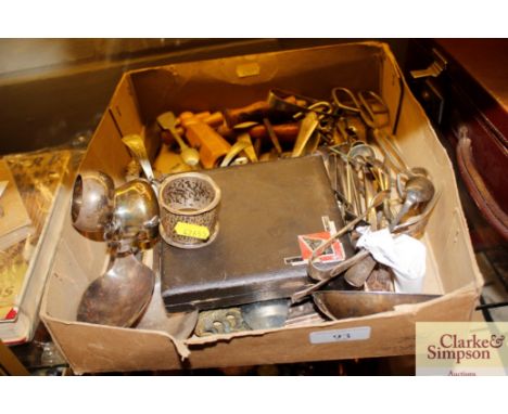 A box of various silver plated ware to include a pair of silver sugar nips, a silver fork and a silver spoon