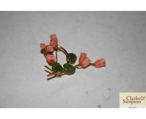 A yellow metal floral brooch with coral flower heads and jade leaves