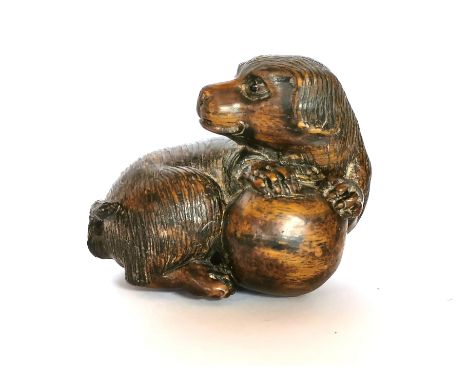 A finely carved fruitwood netsuke with a dog and a ball, with black onyx eyes, H. 4cm. Condition: good.