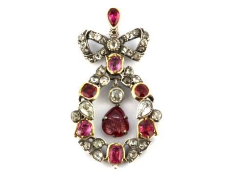 An antique yellow and white metal (tested gold and silver) bow shaped pendant set with old cut rubies and diamonds and a carv