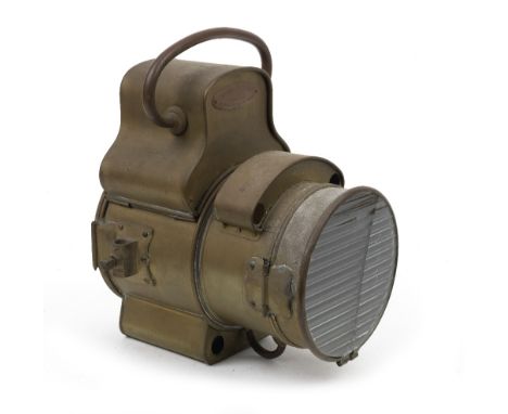 A Salsbury-Flario self-contained acetylene headlamp,brass body, with 6¾ inch ribbed lens (cracked), the fork mounts both stam