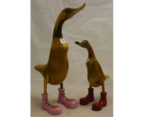 Two wooden model ducks, wearing boots