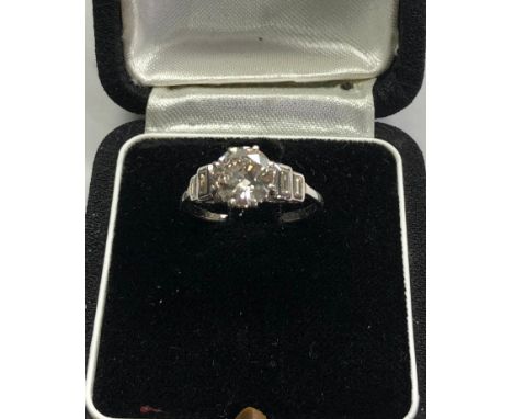 Fine 1.25ct diamond ring central diamond measures approx 7.5mm dia with baguette diamods either side set in platinum 