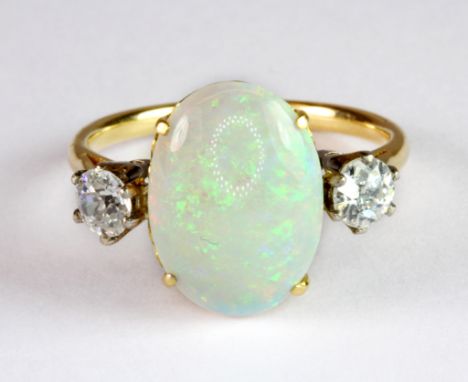 A yellow metal (tested 14ct gold) ring set with a lovely cabochon cut opal and two brilliant cut diamonds (Q.5)