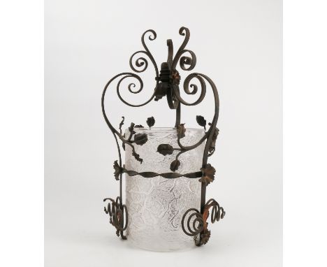 An Arts and Crafts style light fitting, the textured glass cylindrical shade housed in a metal frame decorated with leaves, s
