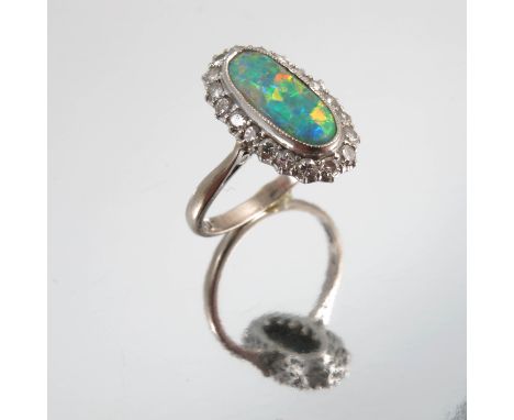 An 18 carat white gold opal and diamond cluster ring, the long shallow cabochon of approximately 12.5mm by 5.5mm by 2.8m deep