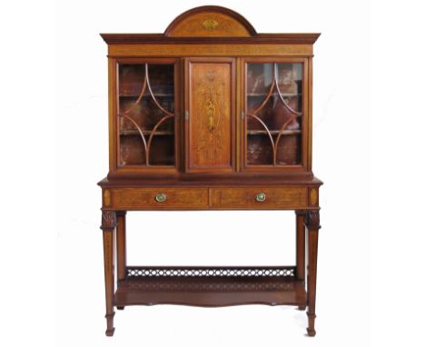 An Edwardian satinwood display cabinet, the arched frieze having a central panel of putti with a basket flanked by scrolls, w