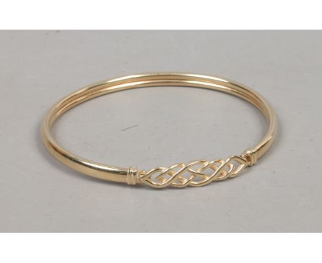 A yellow metal bangle with pierced decoration.