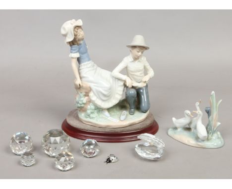 Two Nao ceramic figures, along with seven Swarovski style paperweights.
