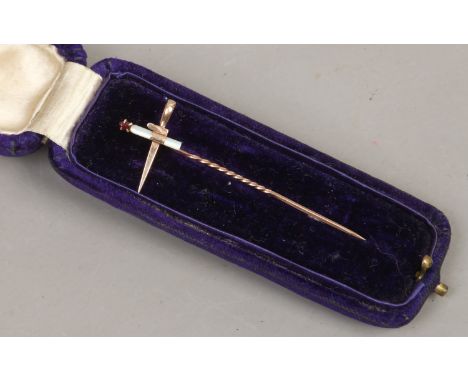 A cased yellow metal stick pin the terminal formed as a dagger and candle set with mother of pearl and garnet.