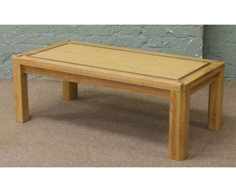 A light oak coffee table crossbanded with dark oak and raised on square cut legs.