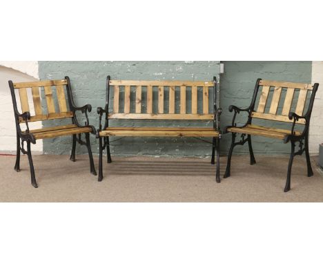 A painted cast iron two seat garden bench along with two matching arm chairs.