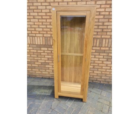 A good quality single door, light oak display cabinet with three bevelled glass panes and glass shelves (shelves not shown in