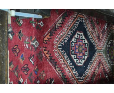 A Persian Shiraz carpet, central linked triple medallion on red ground decorated with birds and flowers with dark spandrels a