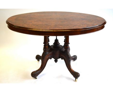 A Victorian burr walnut centre table, the oval tilt top raised on an arrangement of four turned moulded supports to a quad ba