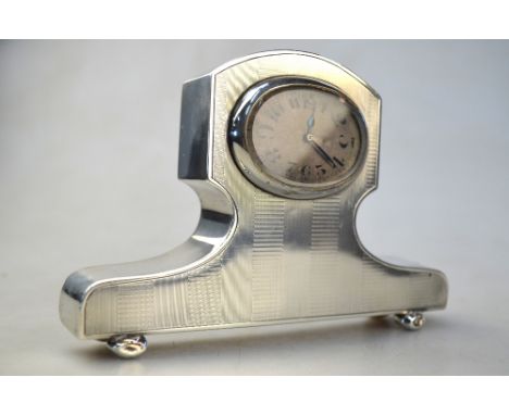 An engine-turned silver desk clock with oval enamel dial, on bun feet, Charles Green & Co. Ltd., Birmingham 1921, 10 x 14 cm
