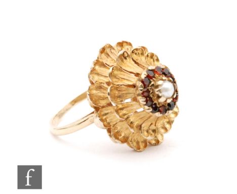 A 9ct garnet and pearl cluster ring, central pearl within a garnet border to a  double stepped floral head, ring size K. 