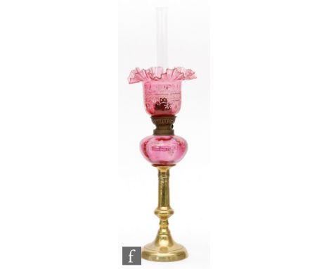 A Victorian oil lamp with a ruby glass shade and reservoir decorated with gilt and enamel designs of flowers and spots on a b