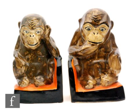 A pair of 1930s Myott book ends in the form of seated chimpanzees with enamelled decoration, raised to a banded base, printed
