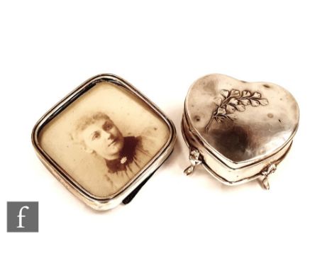 A hallmarked silver heart shaped trinket box with a floral spray to hinged cover and raised on three scroll legs, Birmingham 