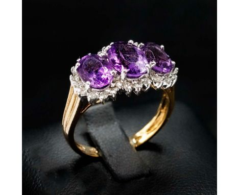A 9CT GOLD AMETHYST AND DIAMOND TRILOGY RING. the white and yellow shank set with amethyst and diamonds, the amethysts of app