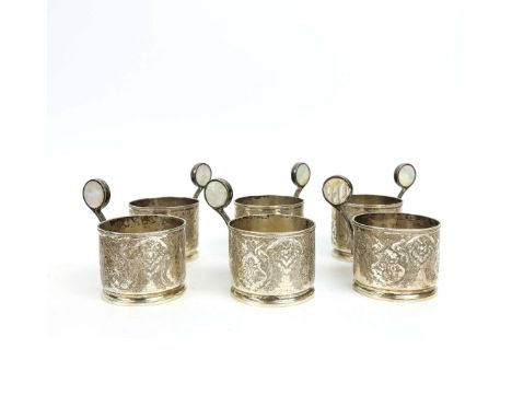A SET OF SIX WHITE METAL DRINKING GLASS HOLDERS. probably Persian, elaborately engraved throughout, with mother-of-pearl inse