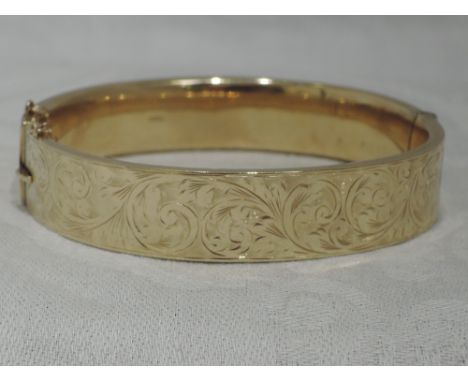 A 9ct gold hinged bangle having engraved scroll decoration, safety chain brokenbANGLE WEIGHT 17.8G INTERNAL DIAMETER 54MM X 6