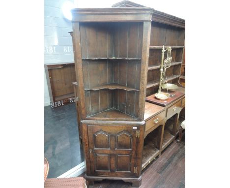 A late 20th century oak period style full height corner cupboard having shelf rack over panel door base