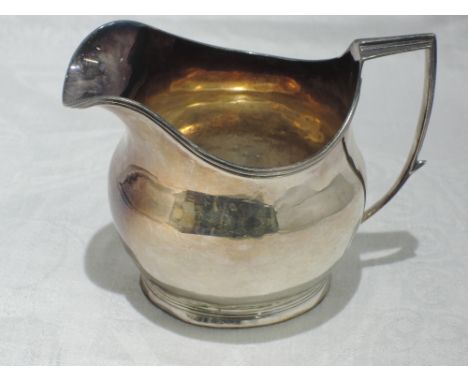A Georgian silver cream jug of helmet form having reided rim and architectural handle, London 1807, makers mark IM