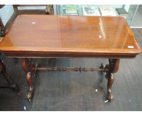 A Victorian mahogany card table having rectangular swivel top on finial lyre frame and quadruple splay legs
