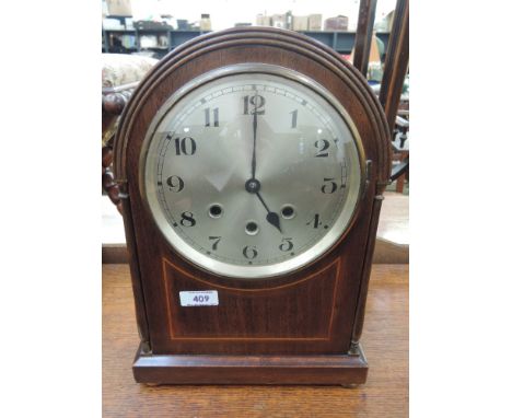 An Edwardian mahogany mantel clock having arch top and circular silvered dial with striking movement