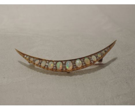 An opal and diamond crescent brooch set with  thirteen graduated opals interspersed by rows of diamond chips in a yellow meta