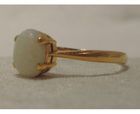 A lady's dress ring having an oval opal in a claw set basket mount on a yellow metal loop stamped 18ct,  size U