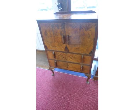 A walnut quarter veneered cabinet, gallery over twin doors opening to reveal shelf above two drawers raised on cabriole suppo