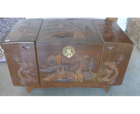 An Oriental camphor wood trunk with carved decoration, hinged lid opening to reveal sliding drawer - 100cm x 50cm x 58cm high