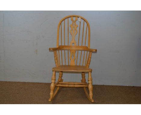 A 20th Century beech Windsor style rocking chair, the hooped back with shaped and pierced splats, above outswept arms and sol