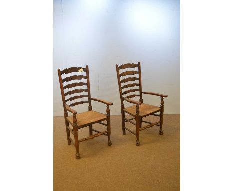 A pair of early 20th Century elm ladder back chairs, the shaped rails contained within turned elm uprights, outswept arms abo