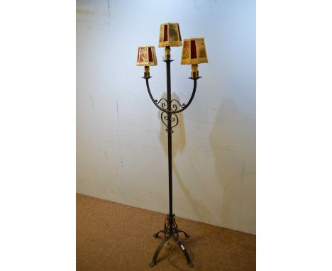 An early 20th Century wrought iron standard lamp, with three branches and metal strapwork, raised on a quadripartite base, 17