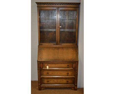 A 20th Century oak bureau bookcase, the projecting cornice above a pair of glazed cupboard doors enclosing adjustable shelves