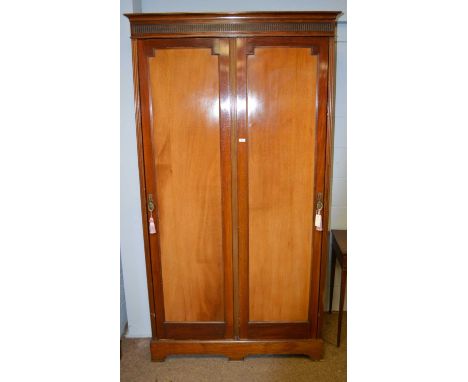 An early 20th Century two-door wardrobe, the projecting cornice above an arcaded frieze and two fielded panel doors enclosing