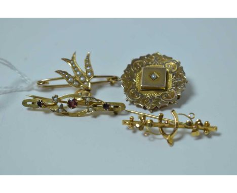 Four Edwardian yellow metal brooches: one swift pattern with heart drop, set seed pearls; another brooch centred by seed pear