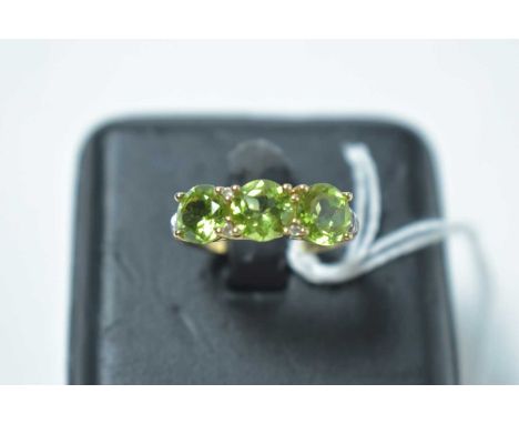 A peridot ring, the three circular cut peridots interspersed by white stones, on 9ct yellow gold shank. 