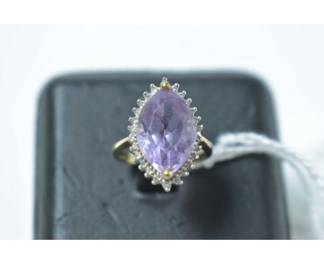 An amethyst and diamond cluster ring, with oval facet cut amethyst, on yellow metal shank, stamped '9K'. 