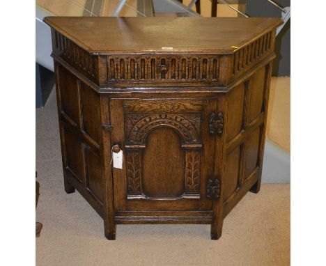 A 20th Century oak side cabinet, the shaped top with canted angle and arcaded frieze, above a single frieze drawer and arcade