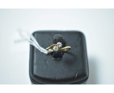 Two stone diamond ring, in cross over mount, on yellow metal shank. 